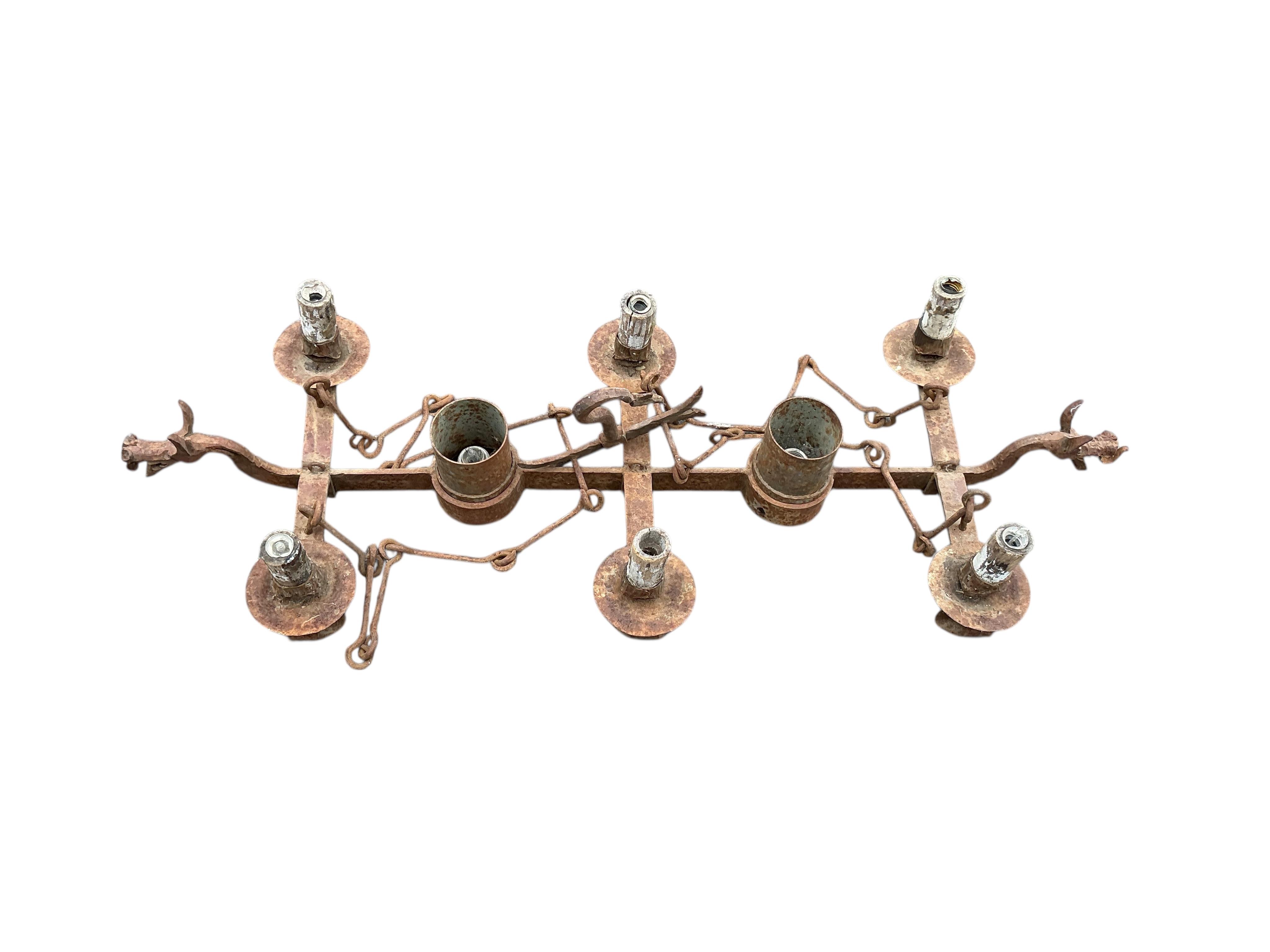 A wrought iron five branch tripod candlestand, height 134cm together with a wrought iron dragon head hanging light fitting